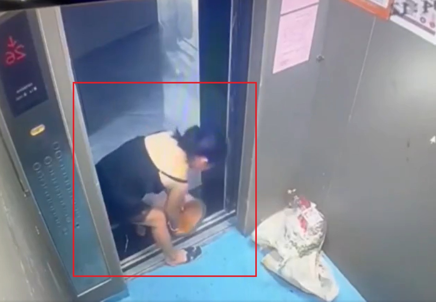 A woman pours trash and dirty water into the elevator.